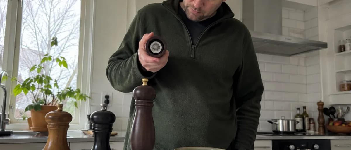 Person som jämför flera pepparkvarnar och tittar på malverket i ett kök