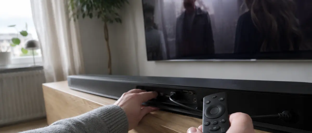 Händer som kontrollerar HDMI-portarna på baksidan av en soundbar